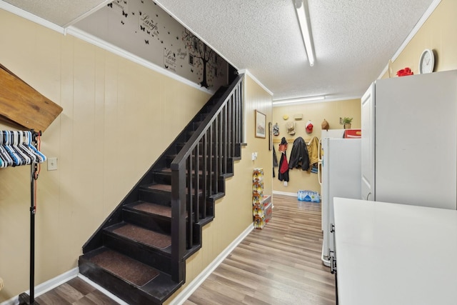 staircase with hardwood / wood-style flooring, crown molding, and a textured ceiling