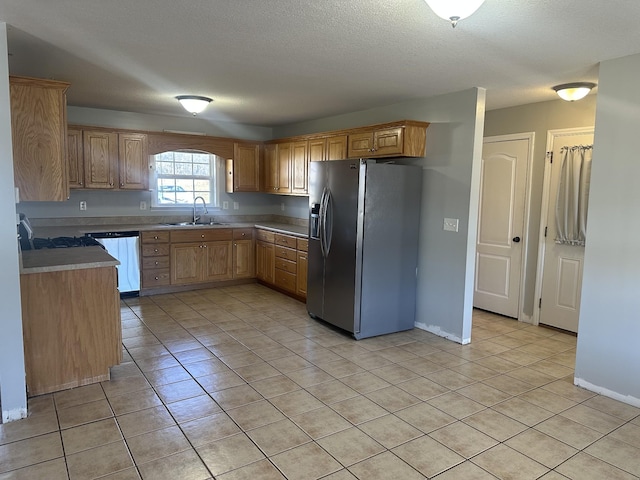 kitchen with sink, dishwasher, stainless steel refrigerator with ice dispenser, a textured ceiling, and light tile patterned flooring