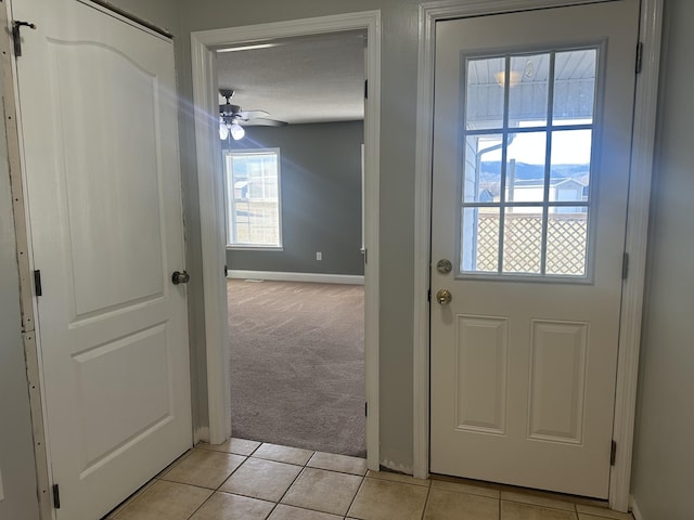 doorway to outside featuring light carpet, ceiling fan, a mountain view, and a textured ceiling