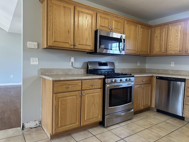 kitchen with appliances with stainless steel finishes, a textured ceiling, and light tile patterned floors