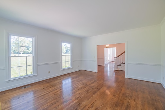 spare room featuring dark hardwood / wood-style flooring, crown molding, and a healthy amount of sunlight