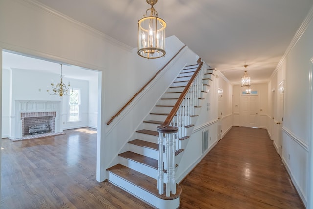 stairway with hardwood / wood-style flooring, ornamental molding, and a notable chandelier