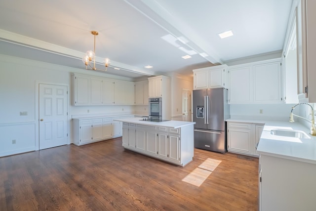 kitchen featuring a kitchen island, high quality fridge, decorative light fixtures, white cabinetry, and sink