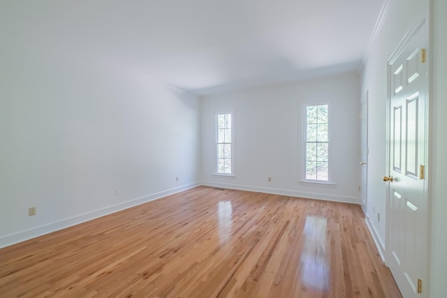 spare room featuring ornamental molding and light wood-type flooring