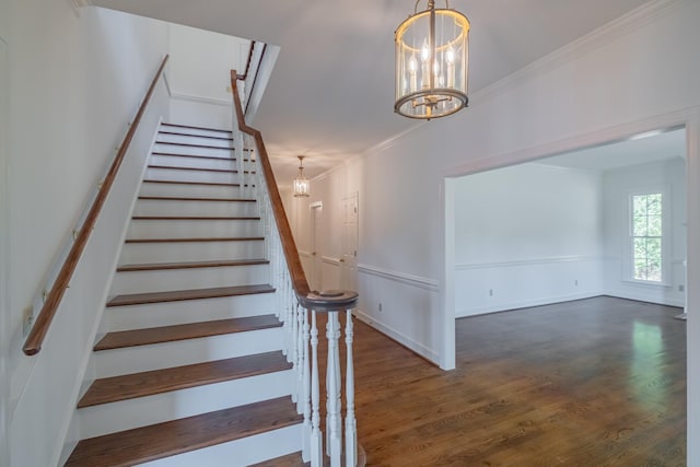 stairs featuring hardwood / wood-style flooring, ornamental molding, and a chandelier