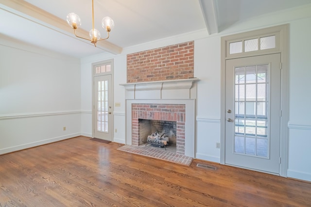 unfurnished living room with beam ceiling, an inviting chandelier, crown molding, hardwood / wood-style flooring, and a fireplace