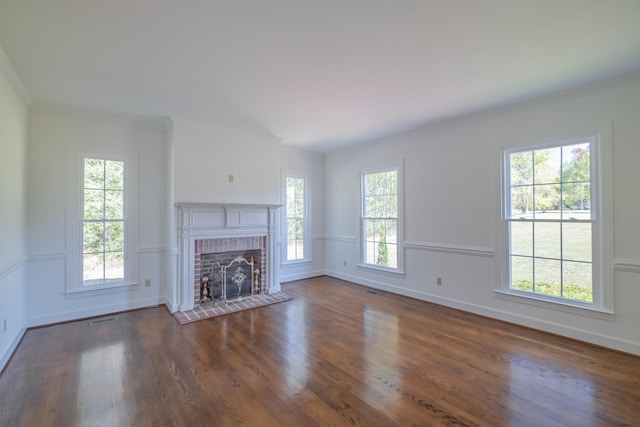 unfurnished living room with ornamental molding, a fireplace, dark hardwood / wood-style flooring, and a wealth of natural light