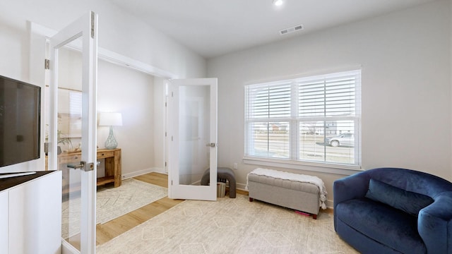 sitting room featuring french doors, visible vents, baseboards, and light wood finished floors