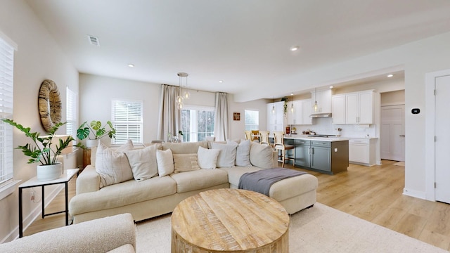 living room with light wood-type flooring, visible vents, baseboards, and recessed lighting