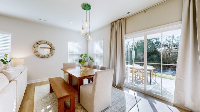 dining room featuring light wood-style flooring, visible vents, and baseboards