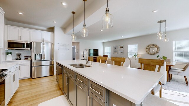 kitchen featuring appliances with stainless steel finishes, a sink, white cabinetry, and a healthy amount of sunlight