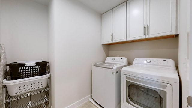 clothes washing area with washer and dryer, cabinet space, and baseboards