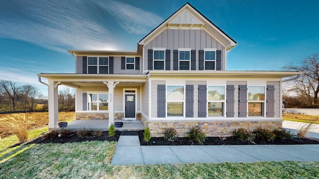 view of front of property featuring stone siding, a porch, and board and batten siding