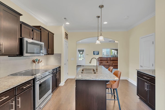 kitchen with appliances with stainless steel finishes, a breakfast bar, pendant lighting, sink, and a center island with sink