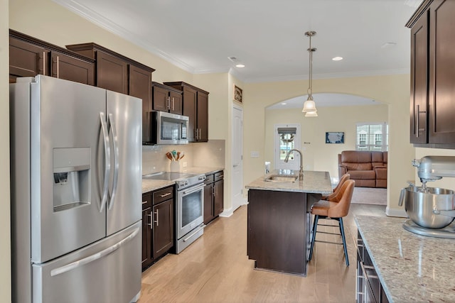 kitchen featuring pendant lighting, sink, a kitchen breakfast bar, stainless steel appliances, and an island with sink