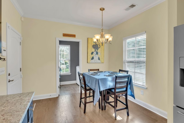 dining room with a notable chandelier, hardwood / wood-style flooring, and ornamental molding