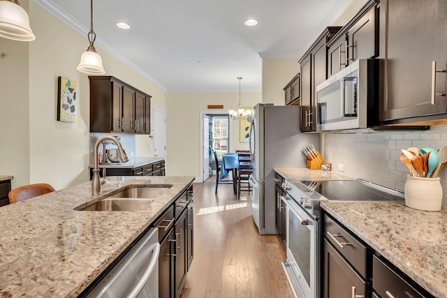 kitchen featuring stainless steel appliances, sink, pendant lighting, and dark brown cabinetry