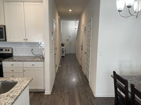 corridor featuring an inviting chandelier and dark hardwood / wood-style floors