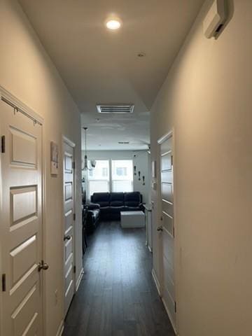 corridor with an AC wall unit and dark wood-type flooring