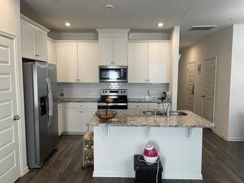 kitchen with a kitchen island with sink, a kitchen bar, white cabinetry, and appliances with stainless steel finishes