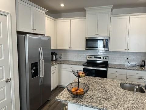 kitchen with white cabinetry, sink, stainless steel appliances, and light stone countertops