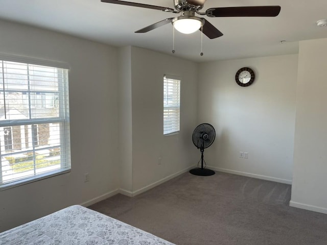 unfurnished bedroom with multiple windows, ceiling fan, and dark colored carpet