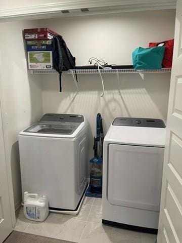 clothes washing area featuring light tile patterned floors and independent washer and dryer