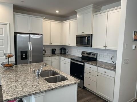 kitchen featuring white cabinetry, stainless steel appliances, and an island with sink