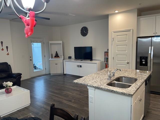 kitchen featuring a center island with sink, white cabinets, appliances with stainless steel finishes, open floor plan, and a sink