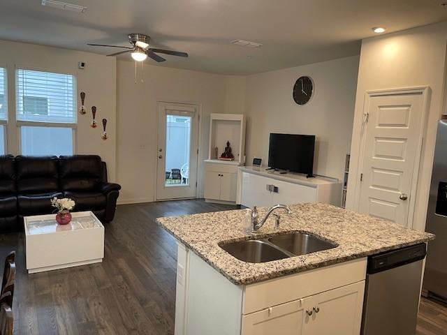 kitchen with dishwasher, open floor plan, a sink, and white cabinets