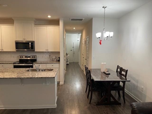 kitchen featuring a breakfast bar area, stainless steel appliances, visible vents, white cabinetry, and a sink