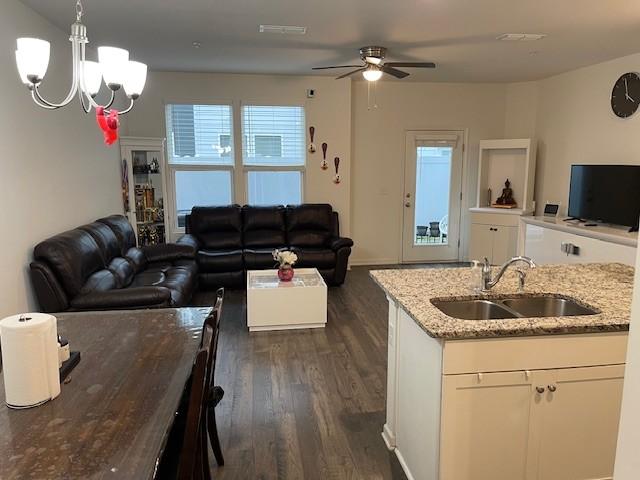 interior space with pendant lighting, white cabinets, a sink, and open floor plan