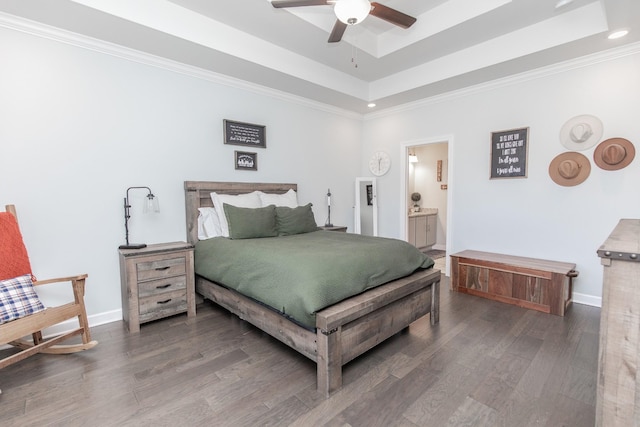 bedroom featuring a raised ceiling, dark wood-type flooring, ceiling fan, and ensuite bath