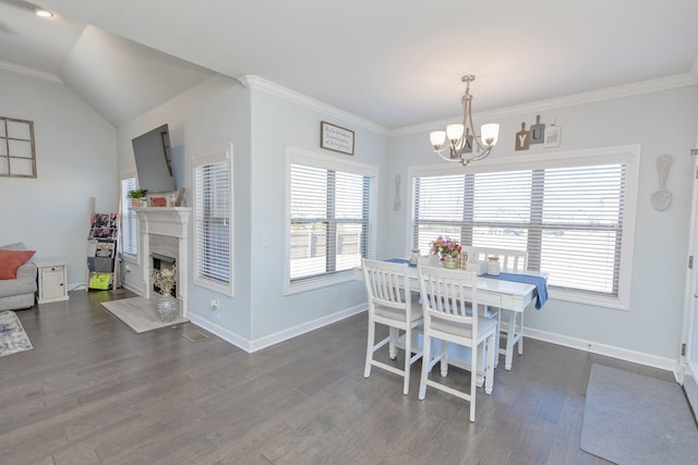 dining space featuring an inviting chandelier, a high end fireplace, dark hardwood / wood-style flooring, and vaulted ceiling