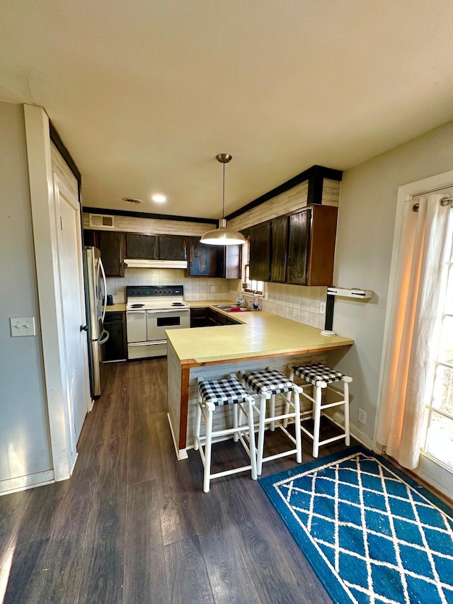 kitchen with a breakfast bar, double oven range, dark brown cabinets, dark hardwood / wood-style floors, and kitchen peninsula