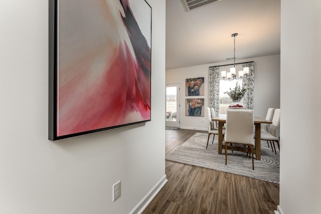 dining area featuring wood-type flooring and an inviting chandelier