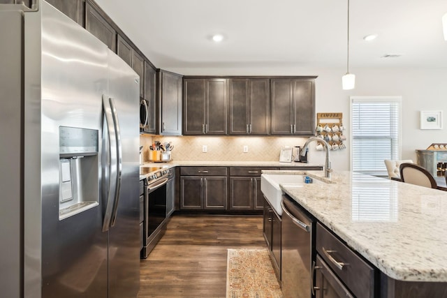 kitchen with dark wood-type flooring, dark brown cabinetry, sink, appliances with stainless steel finishes, and pendant lighting