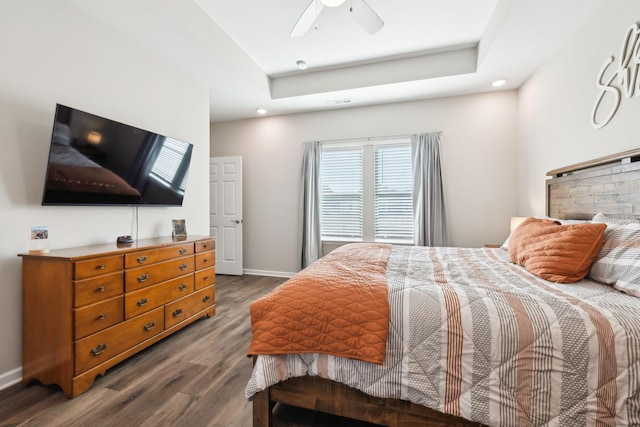 bedroom featuring dark hardwood / wood-style flooring, ceiling fan, and a tray ceiling