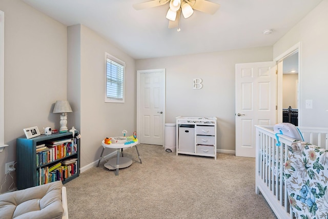 bedroom featuring light carpet, a crib, and ceiling fan