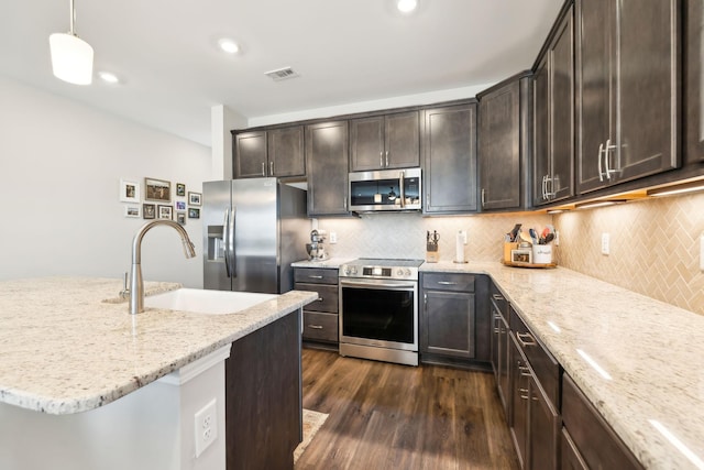 kitchen featuring decorative light fixtures, sink, dark hardwood / wood-style flooring, stainless steel appliances, and light stone countertops