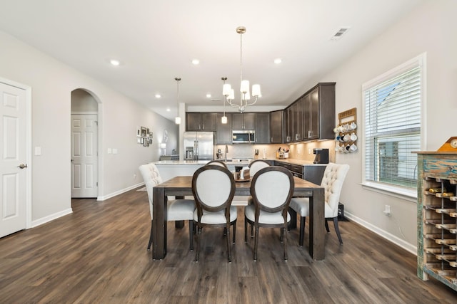 dining space featuring a wealth of natural light, a notable chandelier, and dark hardwood / wood-style flooring