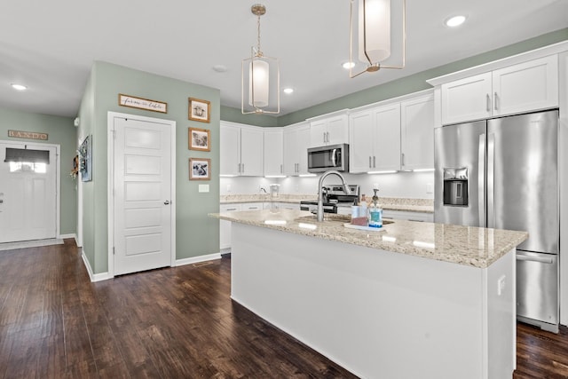 kitchen featuring stainless steel appliances, an island with sink, hanging light fixtures, and white cabinets