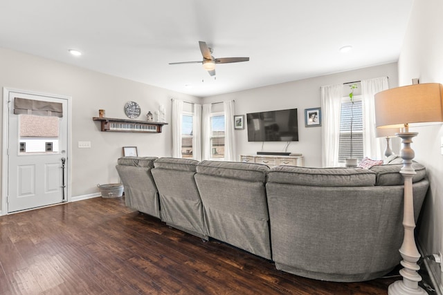 living room featuring dark wood-type flooring, ceiling fan, and plenty of natural light