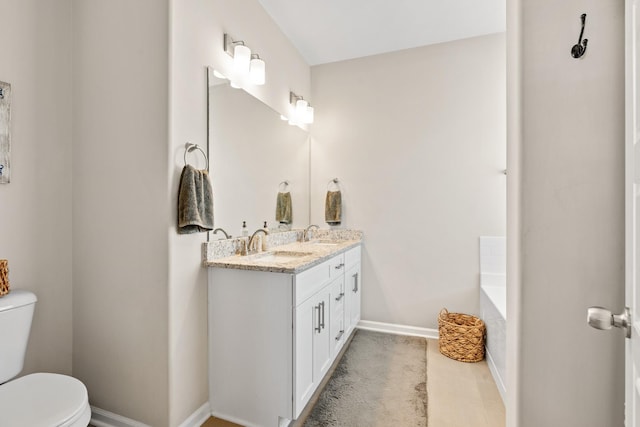 bathroom featuring vanity, a bath, and toilet