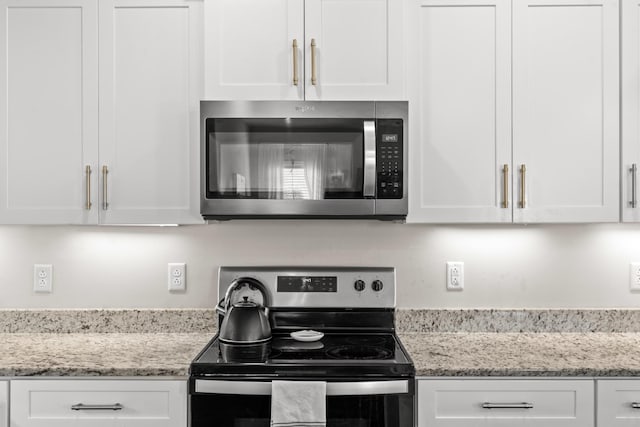 kitchen with white cabinetry, light stone counters, and appliances with stainless steel finishes