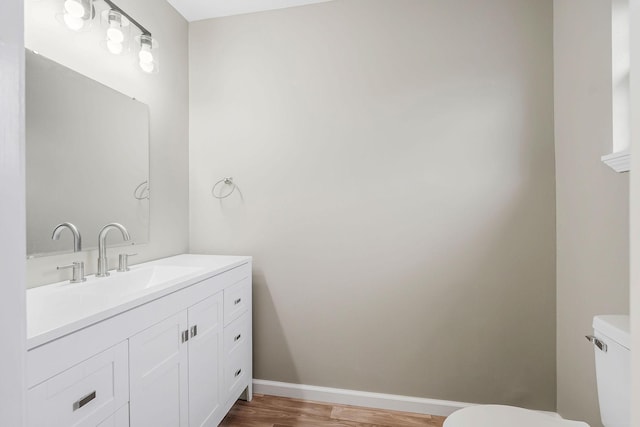 bathroom with hardwood / wood-style flooring, vanity, and toilet