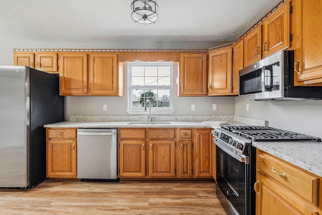 kitchen featuring light stone counters, sink, light hardwood / wood-style flooring, and stainless steel appliances