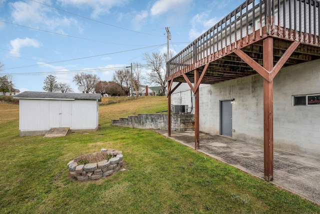 view of yard with a storage unit, central AC, a deck, and a fire pit