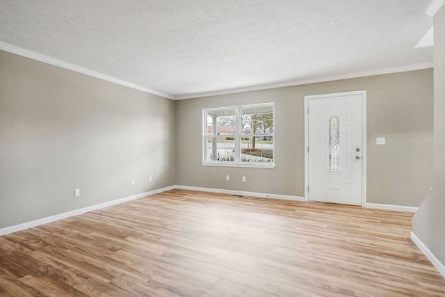 foyer with ornamental molding, light hardwood / wood-style floors, and a textured ceiling