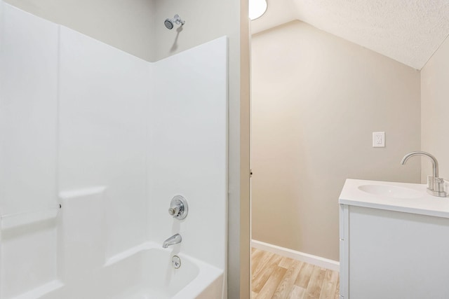 bathroom with lofted ceiling, a textured ceiling, vanity, shower / bath combination, and hardwood / wood-style floors